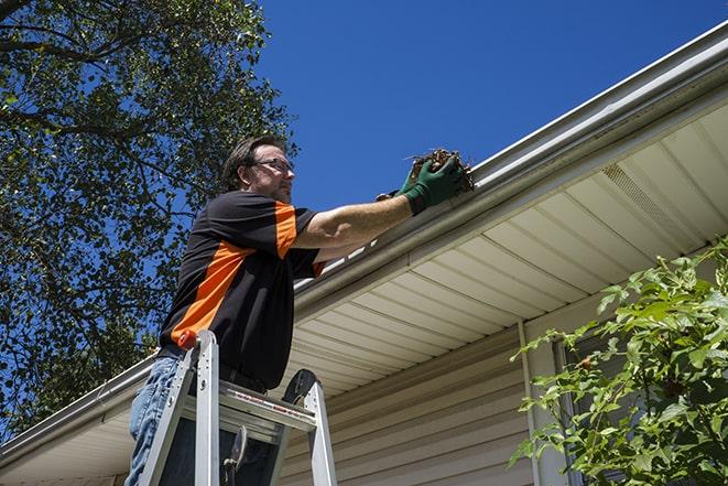 worker installing new gutter system on a roof in Clayton