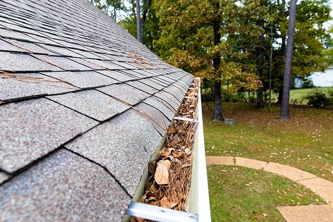 close-up of clogged gutter being cleaned out